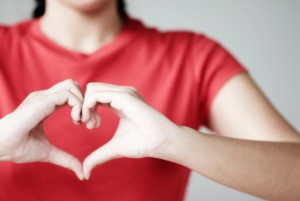 woman forming heart shape over chest