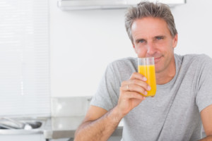 man stands in his kitchen holding a glass of orange juice