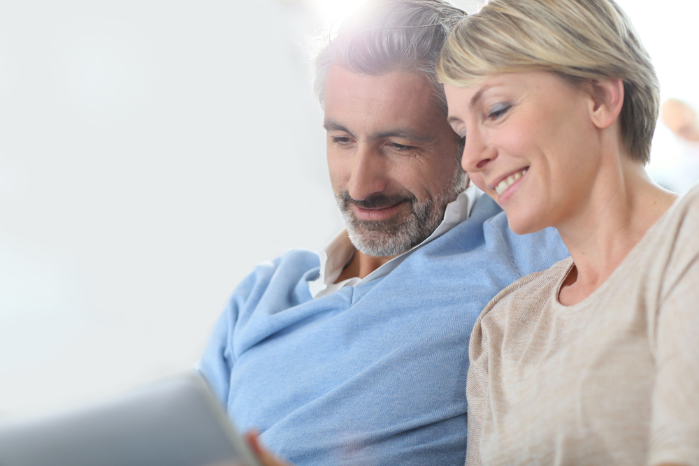 middle aged couple looks up information on a laptop
