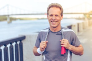 middle aged man smiles while holding a jumprope around his shoulders