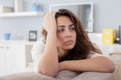 A woman looks very stressed while slouched against the couch